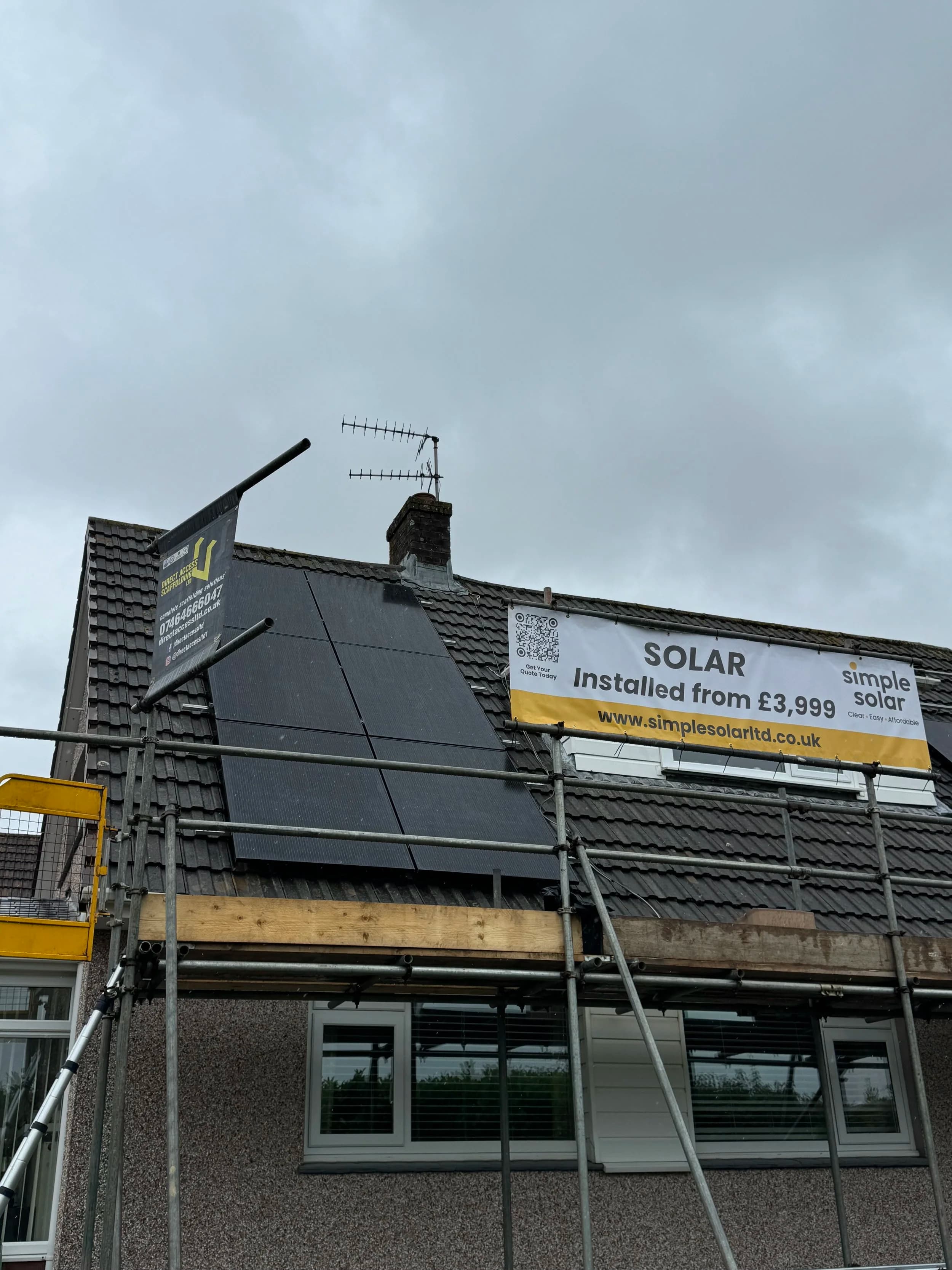 Solar panels on a house at Springfield, Plymouth, with a Simple Solar banner on the scaffolding