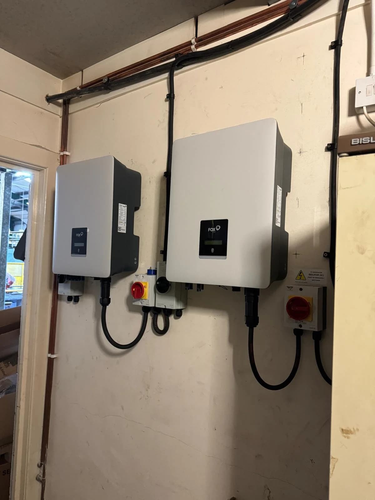 Two inverters with isolator switches wall-mounted inside the workshop